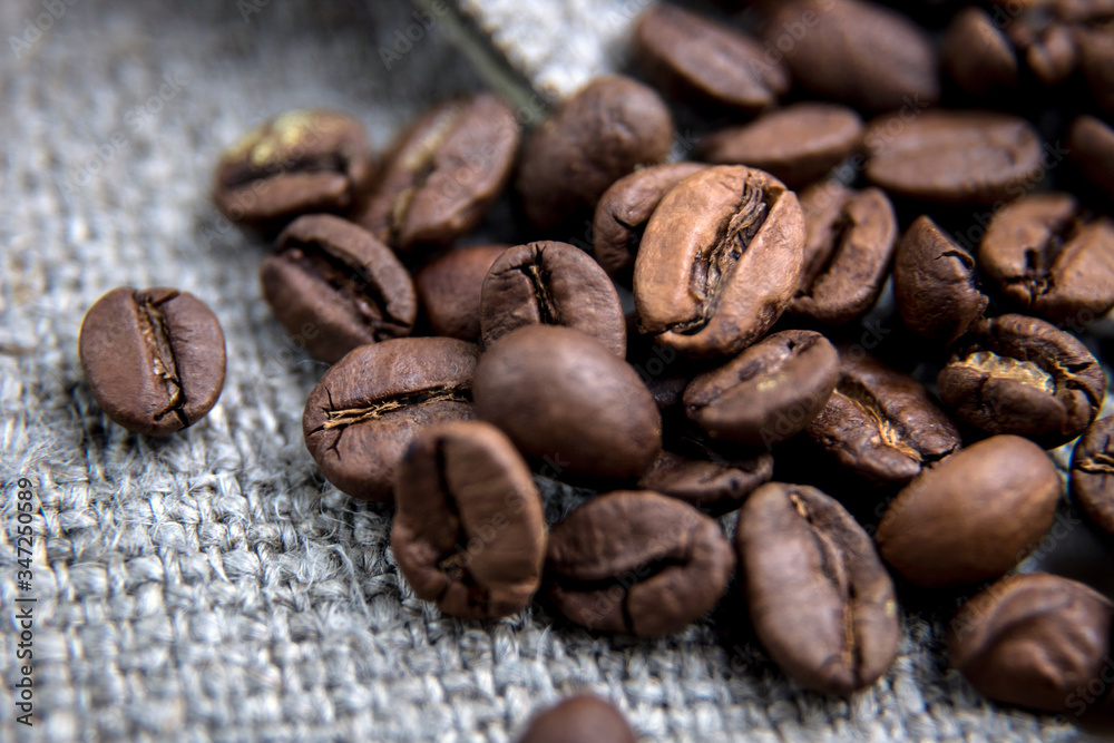 Brown coffee bean close-up.The grains lie on a sacking with a beautiful texture. Macrophotography of coffee. Beautiful grains. Brown coffee bean close-up.The grains lie on a sacking with a beautiful texture. Macrophotography of coffee. Beautiful grains.
