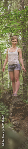 Athletic woman in a tank top and shorts in a forest among green trees