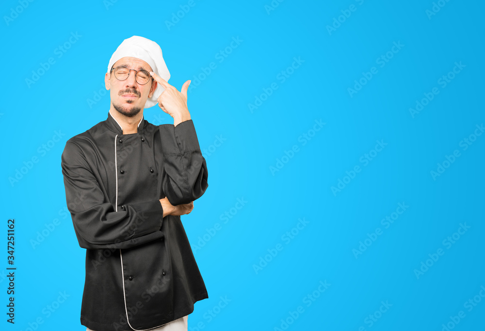 Depressed young chef making a suicide gesture Depressed young chef making a suicide gesture