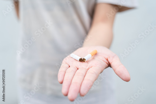 Stop smoking and Quit smoking cigarettes concept. Portrait of beautiful girl holding broken cigarette in hands. Happy female quitting smoking cigarettes. Quit bad habit, health care concept.