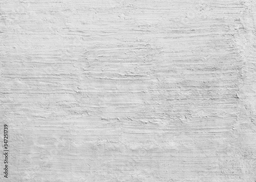Plastered and rough concrete or stone wall painted in white or light gray, hand made stucco texture. High resolution full frame textured background in black and white. Copy space.