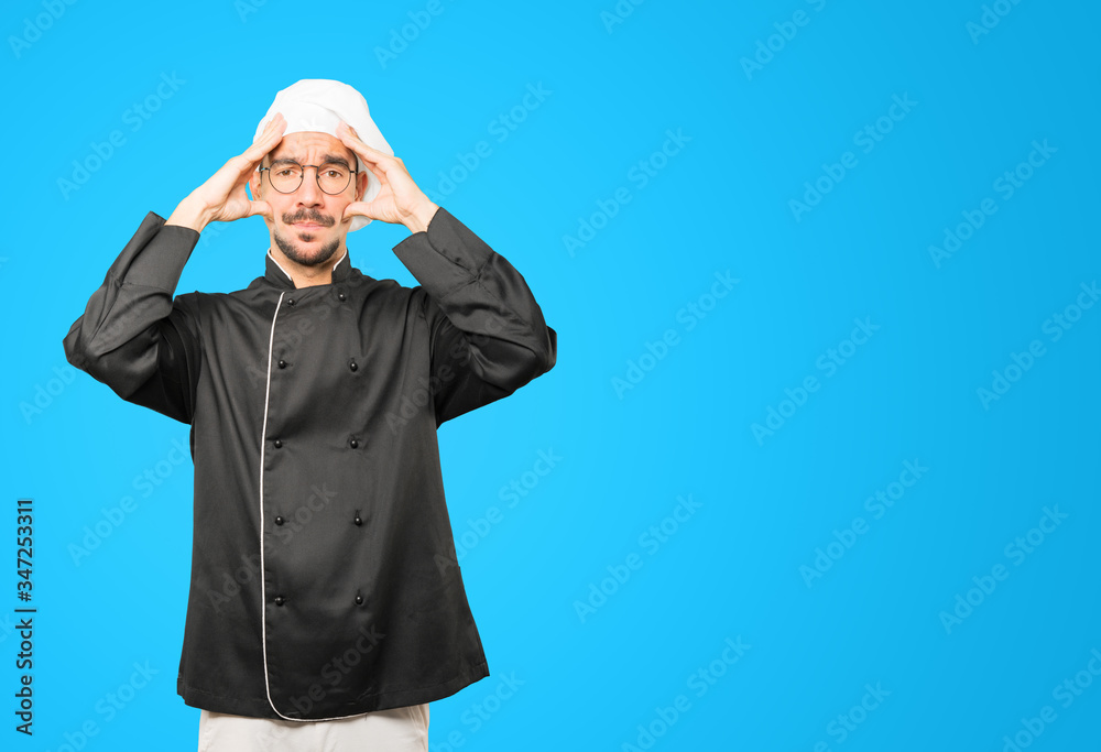 Concerned young chef with a stress gesture Concerned young chef with a stress gesture