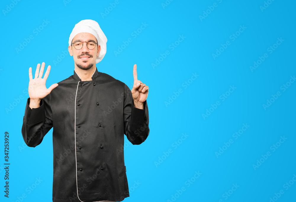 Happy young chef doing a number six gesture with his hands Happy young chef doing a number six gesture with his hands