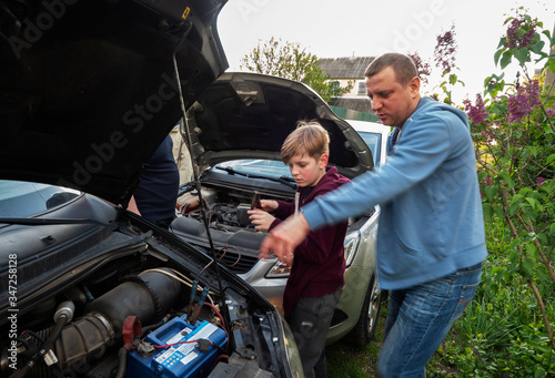 The father explains to his son how to properly connect the battery of another car, if necessary, to start his car in case of breakdown of his own battery © Игорь Головнёв