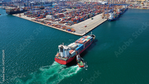 Aerial drone photo of tug boat assisting container cargo ship to dock to logistics international port