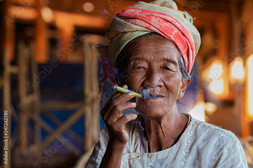 Old lady of Pa O ethnic minority smoking a Burmese cigar at Indein Village near Inle Lake, Shan State, Myanmar (Burma). 