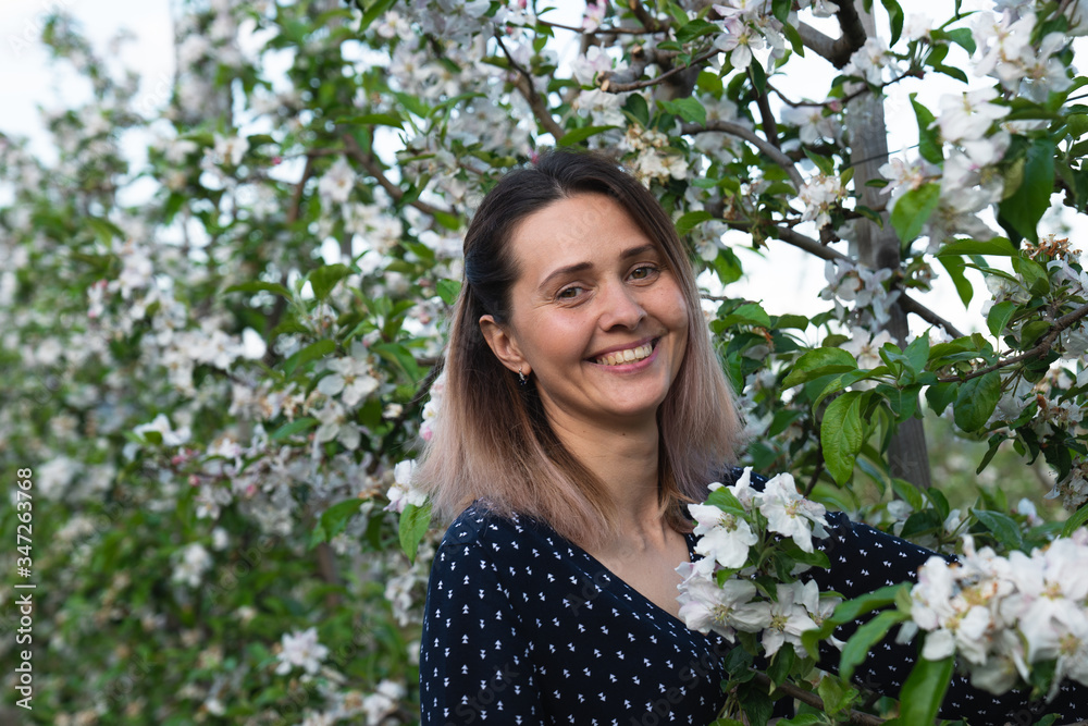 Happy smiling woman among blooming branches looking at the camera Happy smiling woman among blooming branches looking at the camera
