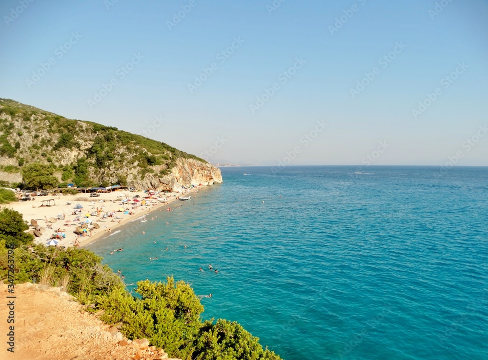 Fotografía de la pintoresca playa de arena blanca y brillante de Gjipe en el Mar Jónico, Albania, escondida entre las empinadas laderas de las montañas y bordeada por el agua clara y color  turquesa