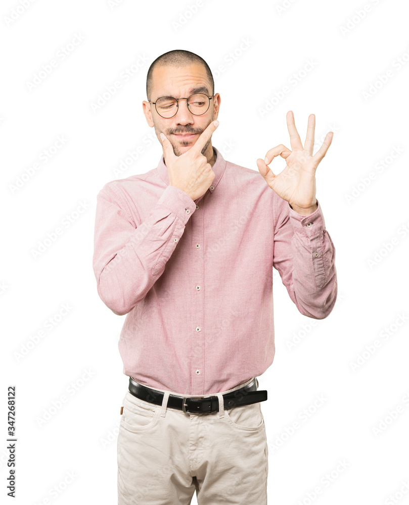 Worried young man doubting and making a gesture of approval Worried young man doubting and making a gesture of approval
