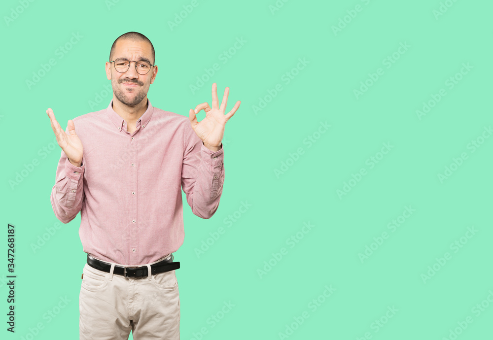 Worried young man doubting and making a gesture of approval Worried young man doubting and making a gesture of approval