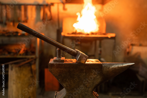 Hammer and anvil in forge on blurred background photo