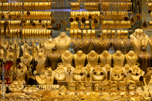 Gold necklaces and bracelets designed in various ways in front of the store. Close-up.