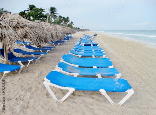 Fotografía de las tradicionales sombrillas con techo de ramas de palmera y hamacas muy ordenadas de color azul en la playa de Varadero, Cuba,  un día sin gente  © Jose Francisco