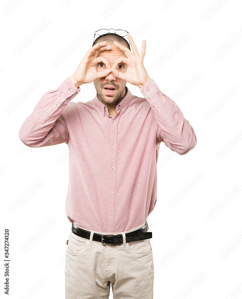 Amazed young man using his hands like a binoculars Amazed young man using his hands like a binoculars