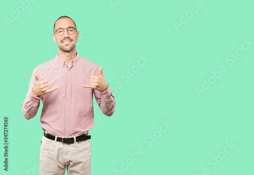 Happy young man making a gesture of calling with the hand