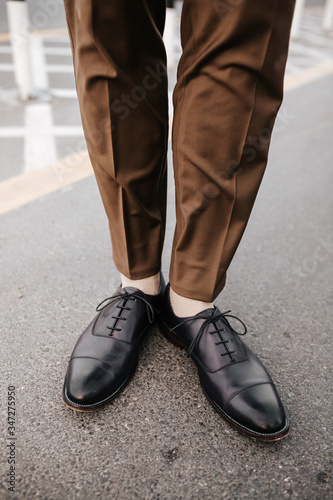 Man’s feet image with brown trouser and black leather shoes for fashion magazine outdoor photography concept.