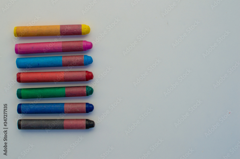 Naklejka premium colored crayons on white background