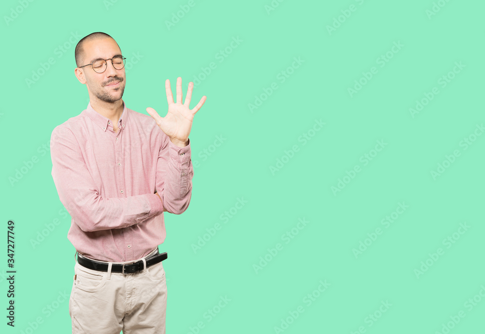 Young man making a number five gesture