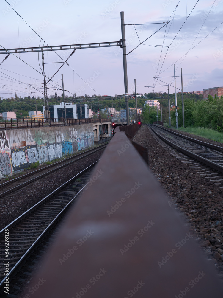 
czech railway tracks at sunset and in the background is prague architecture in spring 2020