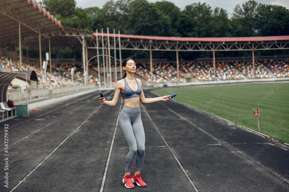 Beautiful girl at the stadium. Sports girl in a sportswear. Lady with jump rope