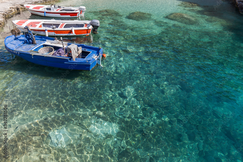 typical wooden fishing boats anchored in a beautiful bay with clear turquoise sea water, Zakynthos island, Greece