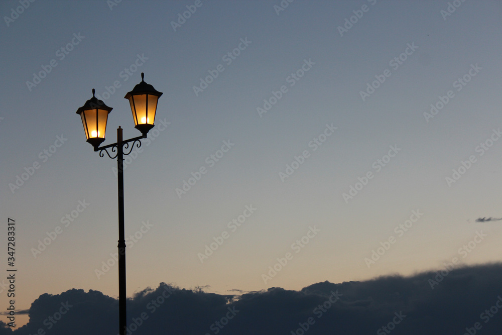Two lamps against the sky with clouds