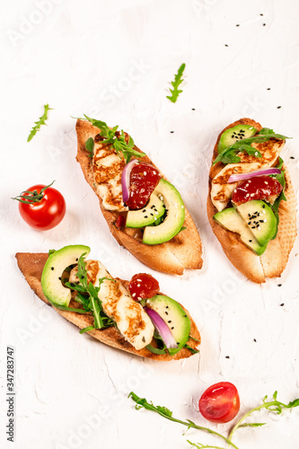 Healthy toasts with grilled Halloumi cheese and slices of avocado on a light background. Healthy vegetarian food. Top view, overhead, cuisine of Cyprus