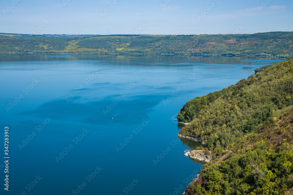 top view landscape wallpaper concept picture of summer July nature scenery with highland forest cover hill and lake reservoir blue water surface