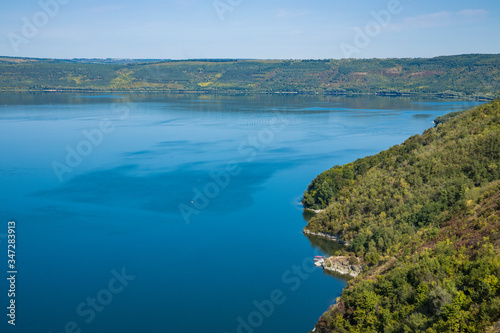 top view landscape wallpaper concept picture of summer July nature scenery with highland forest cover hill and lake reservoir blue water surface