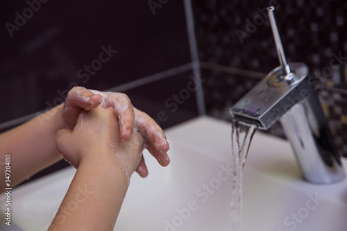 washing hands with antibacterial soap close up on dark background. female washes her hands in the sink under the faucet