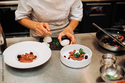 Michelin chef serving food for guests in the kitchen, french cuisine, close up, crop on hands