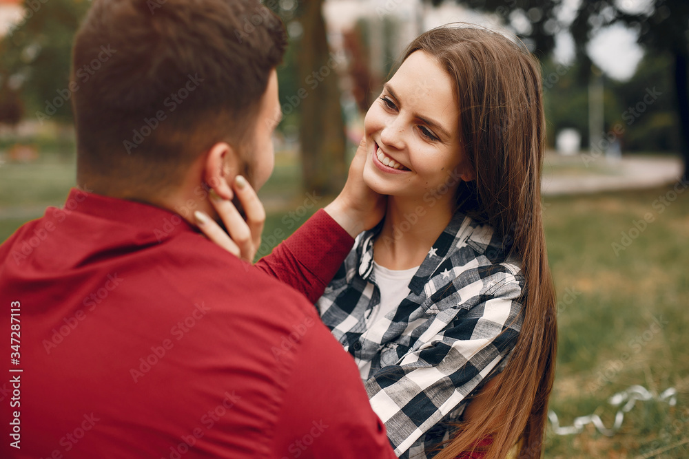 Cute couple in a park. Lady in a chirt. Guy in a red shirt