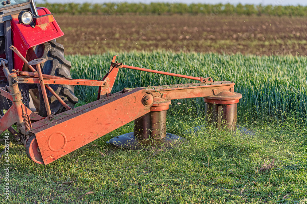 A tractor with implements mower cuts clover. Tractor mowing paddock A tractor with implements mower cuts clover. Tractor mowing paddock