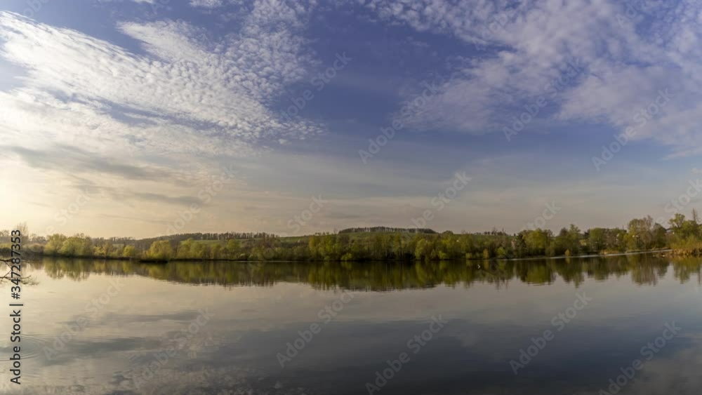 Timelapse of a lake over which clouds move with reflection on the water surface during the afternoon time until sunset with multi colored clouds near the town of Hustopece nad Becvou. Timelapse of a lake over which clouds move with reflection on the water surface during the afternoon time until sunset with multi colored clouds near the town of Hustopece nad Becvou.