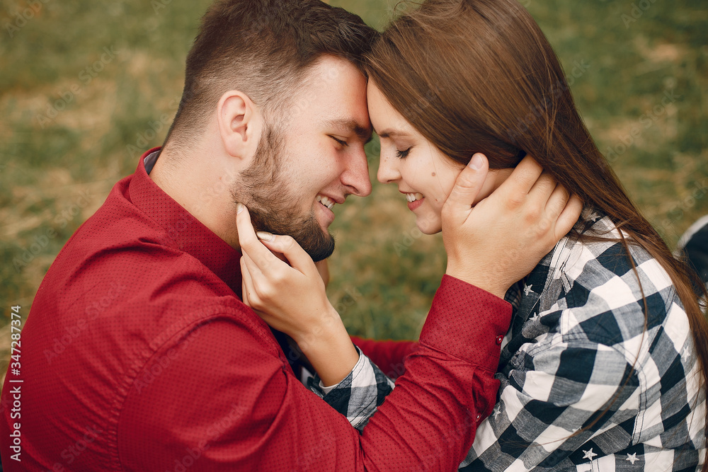 Fototapeta premium Cute couple in a park. Lady in a chirt. Guy in a red shirt