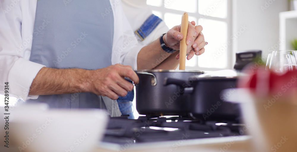 Couple cooking together in the kitchen at home Couple cooking together in the kitchen at home