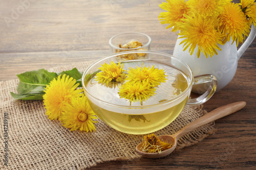 Cup ph healthy dandelion tea on vintage wooden background. Fresh herbs.