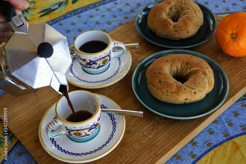 Espresso coffee pouring from a classic stovetop pot at colorful table with sweet, baked Italian yeast donuts. photo