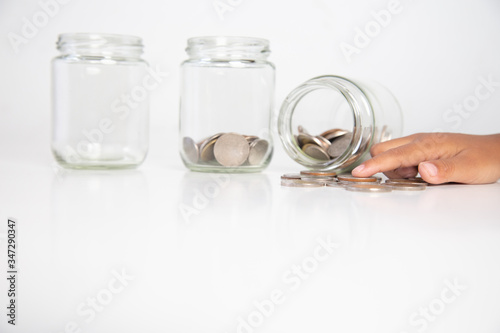  child's hand holding a coin in a glass bottle,.Concept: saving coin family money for home dreams,.symbol growing investment success wealth to benefit,.business growth banking for cash