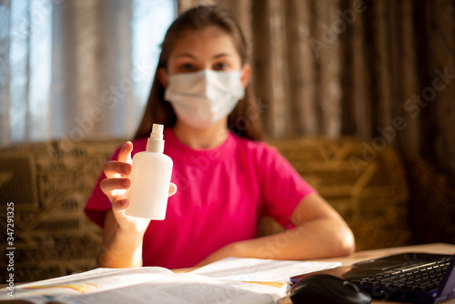 Girl in pink t-shirt and medical mask showing hand santizer to the camera photo