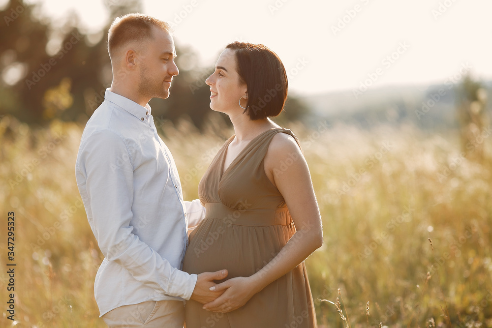 Pragnant woman. Family in a field. Man in a white shirt Pragnant woman. Family in a field. Man in a white shirt