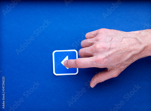Un pictogramme imprimé de bouton play sur lequel une main d'homme clique, sur fond bleu photo