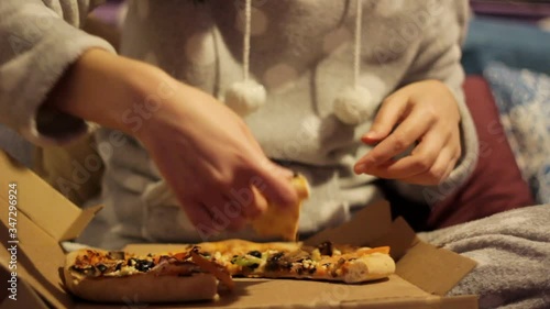 Woman eating pizza at home in her pajamas and watching tv