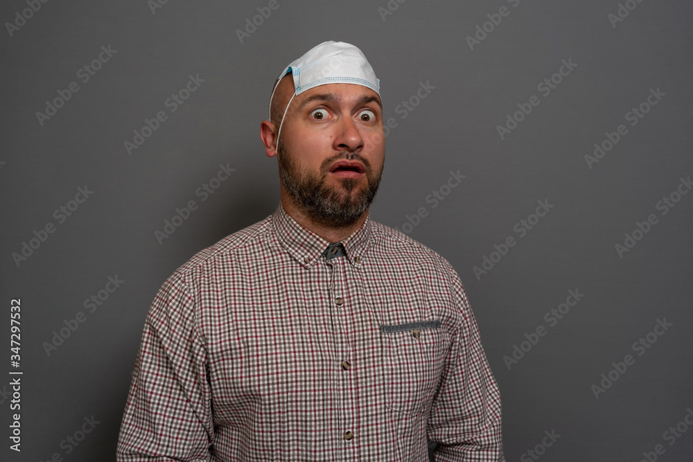Portrait of funny young man in white shirt with surgical medical mask with funny face indoor studio shoot, isolated on gray background. Portrait of funny young man in white shirt with surgical medical mask with funny face indoor studio shoot, isolated on gray background.