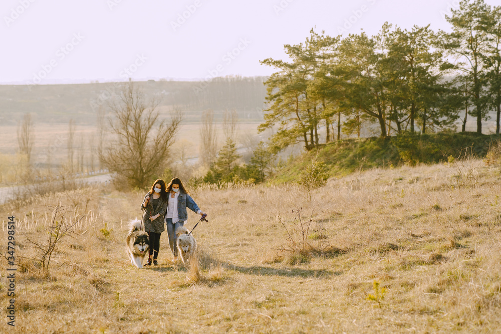 Women in a masks in a spring forest. Girls with cute dogs. Corona virus.