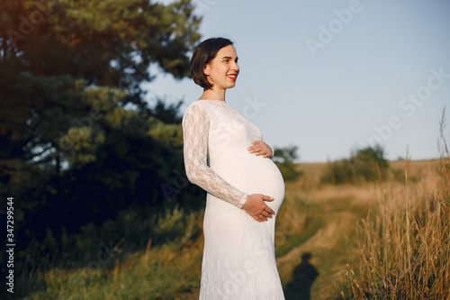 Pragnant woman. Lady in a field. Mother in a white dress