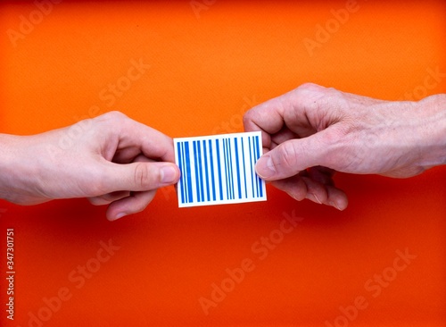 Illustration identification permanente des personnes et des biens, un code barre imprimé tenu par deux mains en opposition, sur fond orange photo