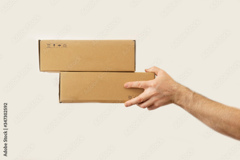 man's hand gives two boxes. dark white background. delivery concept.