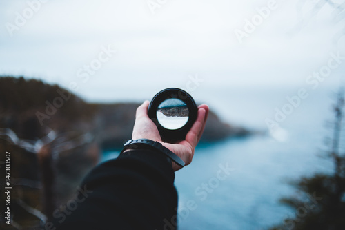 young man holding lens in front of ocean background photo