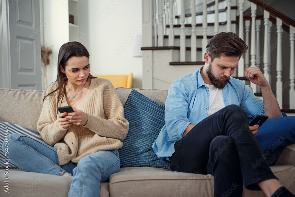 Portrait of young couple standing back to each other and looking at the phone. Portrait of young couple standing back to each other and looking at the phone.